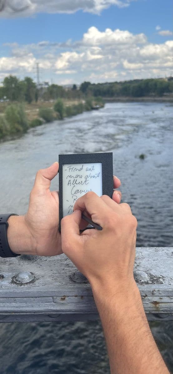 Writing a note on Kairon on a bridge, outdoors
